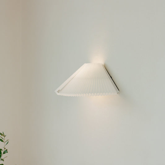 Vegglampen Nebra Wall Lamp fra New Works kombinerer klassisk design med funksjonalitet på poetisk vis: Den plisserte lampeskjermen er justerbar for å kunne tilpasses etter varierende lysbehov året gjennom og hvilken stemning man ønsker å skape i rommet.