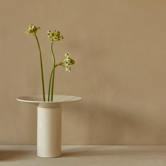 Vasen Hana fra Audo Copenhagen i glasert steintøy er inspirert av Ikebana, den eldgamle japanske kunsten å arrangere blomster. Superfin når du kun vil vise frem noen få, men vakre blomster! Fjerner du toppdelen (som heter kenzan) med de små hullene kan den selvfølgelig også romme en større bukett.