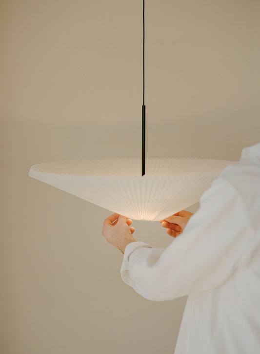 Taklampen Nebra Pendant Lamp fra New Works kombinerer klassisk design med funksjonalitet på poetisk vis: Den plisserte lampeskjermen er justerbar for å kunne tilpasses etter varierende lysbehov året gjennom og hvilken stemning man ønsker å skape i rommet – med et enkelt grep kan du 'vrenge' skjermen og velge om du vil kaste lyset oppover, nedover eller begge deler samtidig. Smart – og fint!