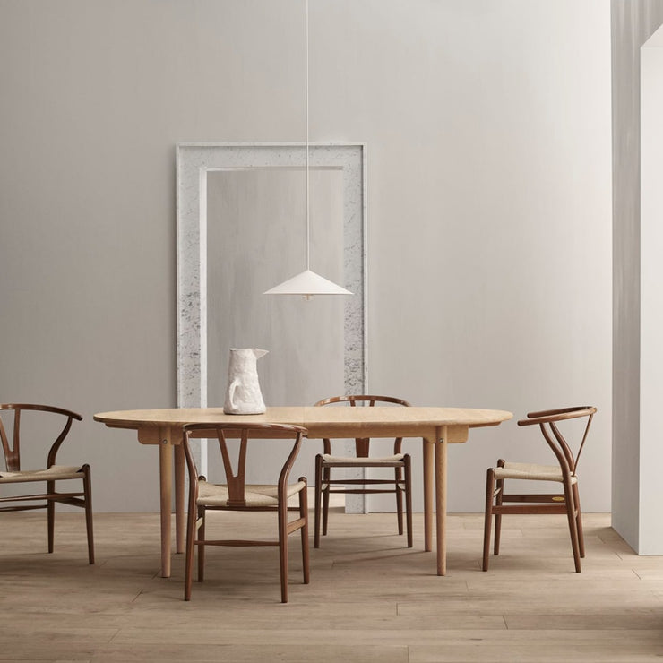 CH337/ CH338 / CH339 Dining Table er spisebord designet av Hans J. Wegner fra Carl Hansen & Søn. Spisebordet, som er laget i heltre, har en innbydende elliptisk formet bordplate som kan forlenges med ileggsplater når du trenger litt ekstra plass. Her er spisebordet i hvitoljet eik, CH338.